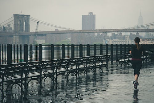 Renowned family physician and running expert, Dr. Antoinette Cheney, DO says beginners should start slow to avoid injury. Image of woman running near Brooklyn Bridge.