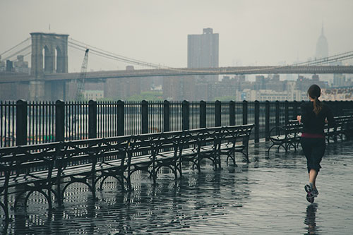 Renowned family physician and running expert, Dr. Antoinette Cheney, DO says beginners should start slow to avoid injury. Image of woman running near Brooklyn Bridge. 