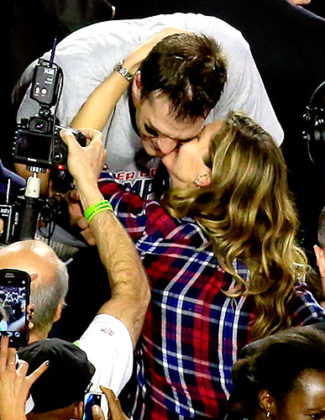 Super Bowl MVP Tom Brady of the New England Patriots kisses his wife Gisele Bundchen (in a red and blue Rails plaid top) after defeating the Seattle Seahawks. Credit: Jamie Squire/Getty Images Image courtesy of US Magazine.