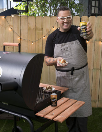 Acclaimed chef Graham Elliot serves his GrahamBurger, which he created to pair with the refreshing flavor of mike’s hard lemonade, at happy hour in the mike’s pop-up backyard on the Magnificent Mile, Friday, May 15, 2015 in Chicago, Ill. (Ross Dettman/AP Images for mike’s hard lemonade)