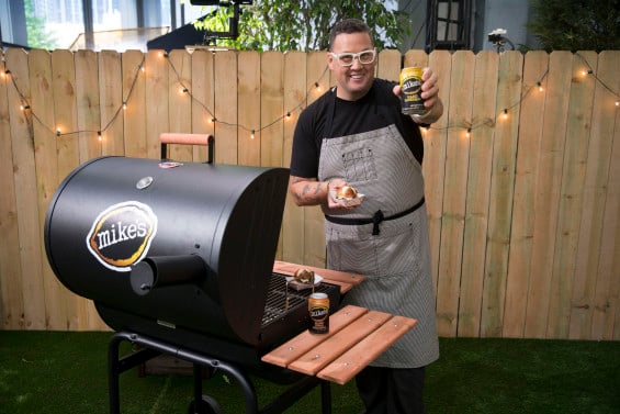 Acclaimed chef Graham Elliot serves his GrahamBurger, which he created to pair with the refreshing flavor of mike’s hard lemonade, at happy hour in the mike’s pop-up backyard on the Magnificent Mile, Friday, May 15, 2015 in Chicago, Ill. (Ross Dettman/AP Images for mike’s hard lemonade)