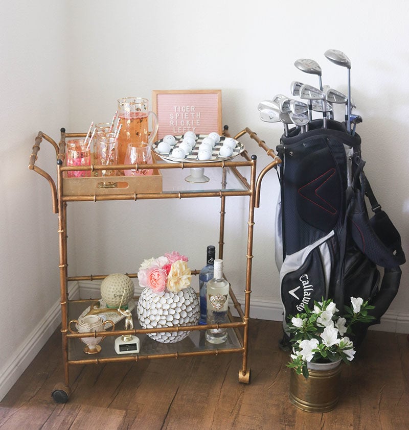 Lifestyle blogger Candie Anderson of the website Candieanderson.com shares her gold faux bamboo bar cart filled with RoseCandi fresh garden roses, Mackenzie Childs black and white courtly check egg plate, golf balls, decor and a golf bag.