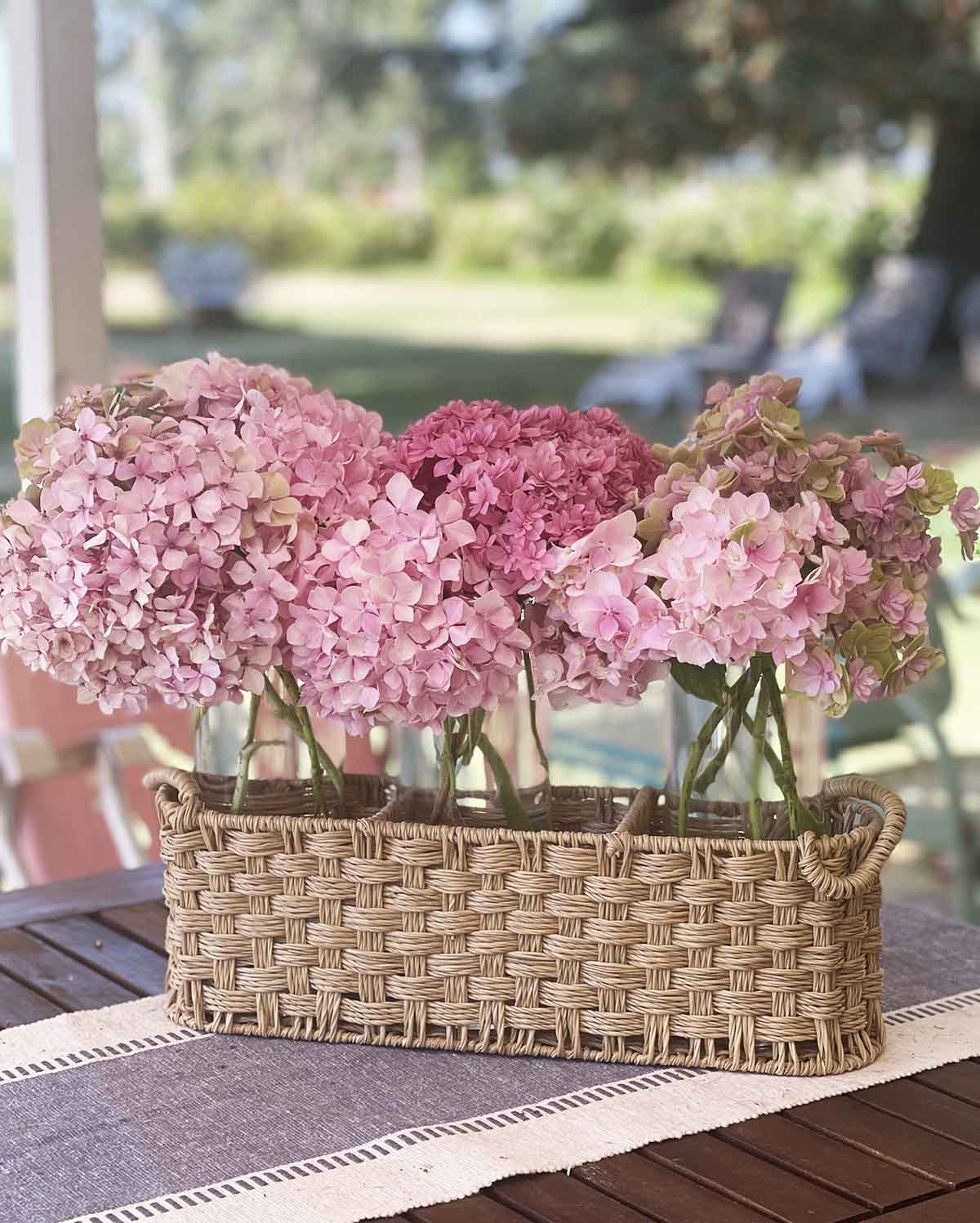how to create a coastal centerpiece with a rattan caddy and glass vases filled with pink hydrangeas. 