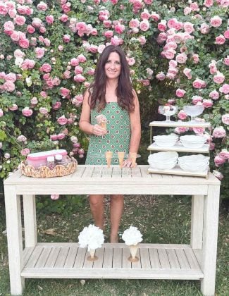Entertaining expert Candie Anderson holding rocky road ice cream cone at ice cream sundae bar station in her rose garden.