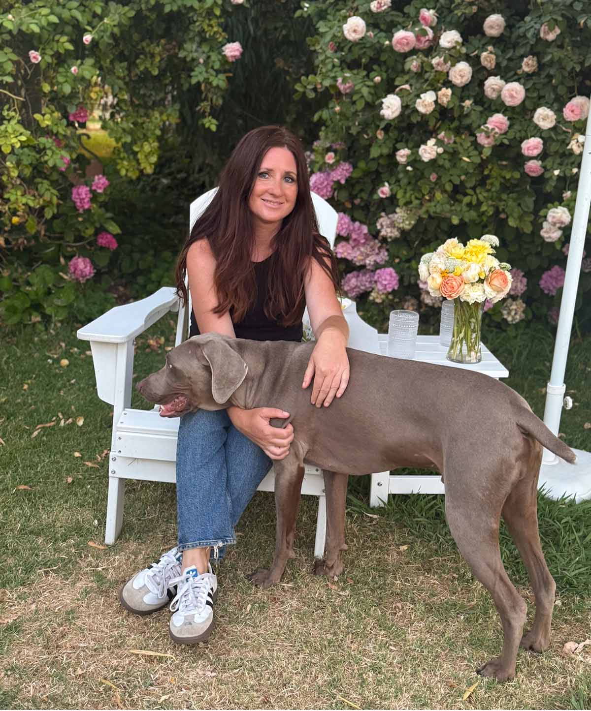 Lifestyle and entertaining expert Candie Anderson and her dog Griffey (a Weimaraner) sitting in her white Adirondack chairs over the summer.