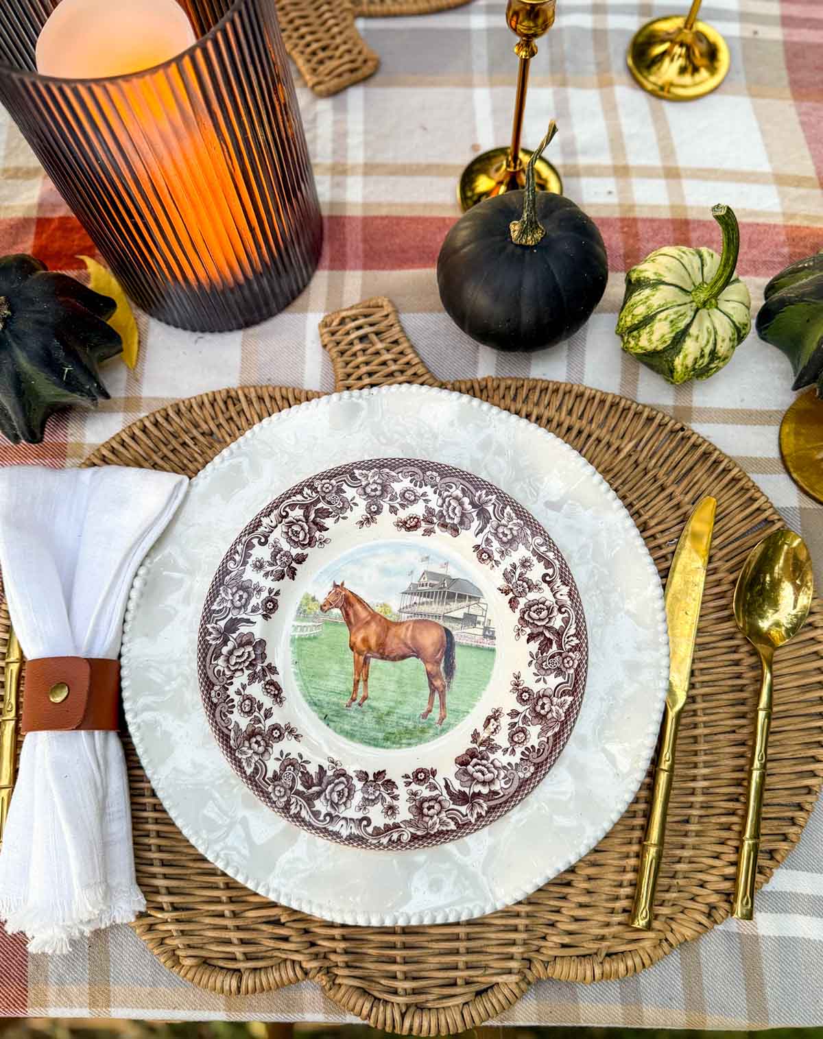 Entertaining expert, Candie Anderson created an elegant outdoor fall tablescape with layered place setting, pumpkin shaped rattan placemats, white perlette plates, and Spode Equestrian horse plates.