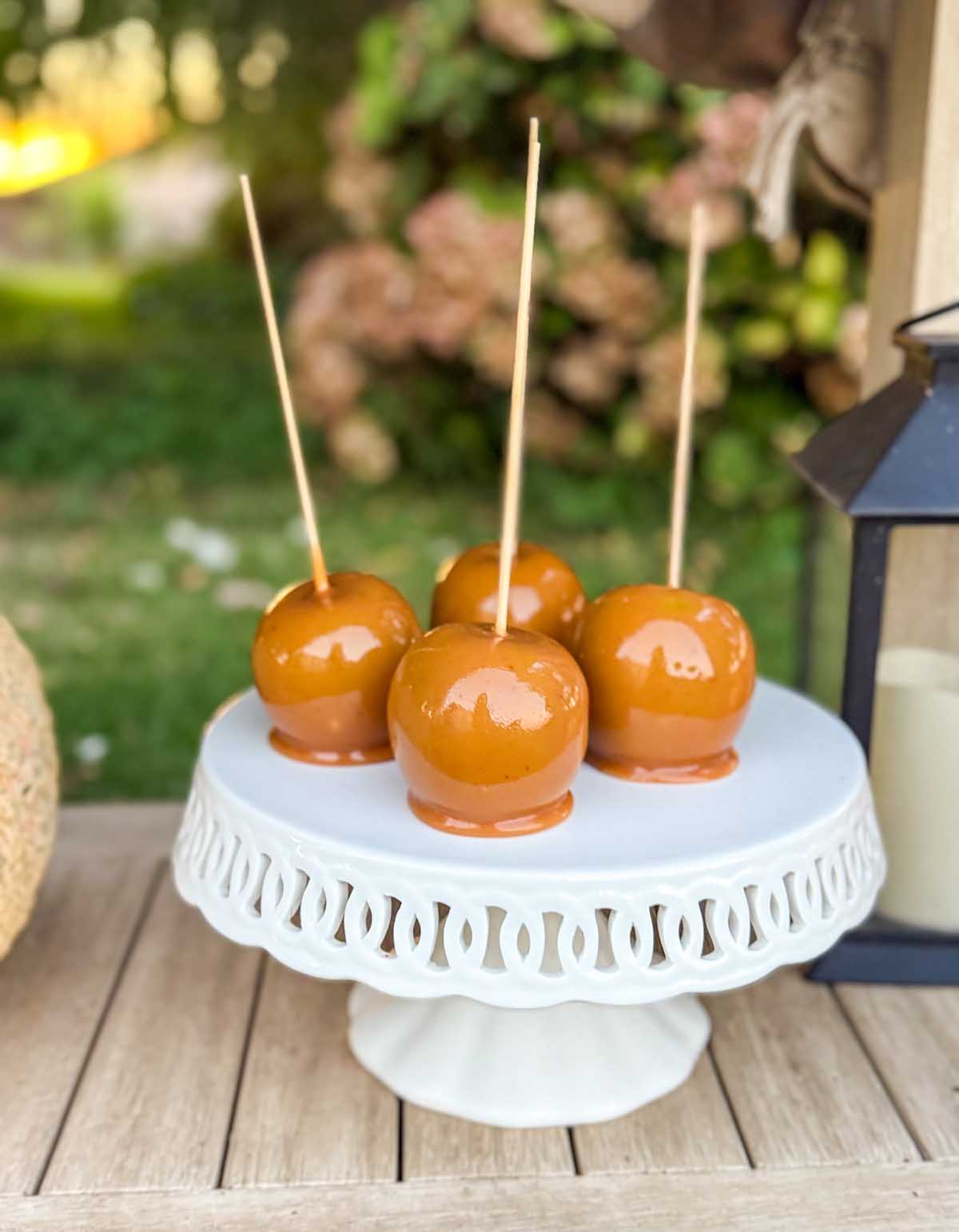 Entertaining expert, journalist and lifestyle blogger Candie Anderson of candieanderson.com shares the beautiful homemade caramel apples (her mom made) on a white cake stand on her fall dessert table.