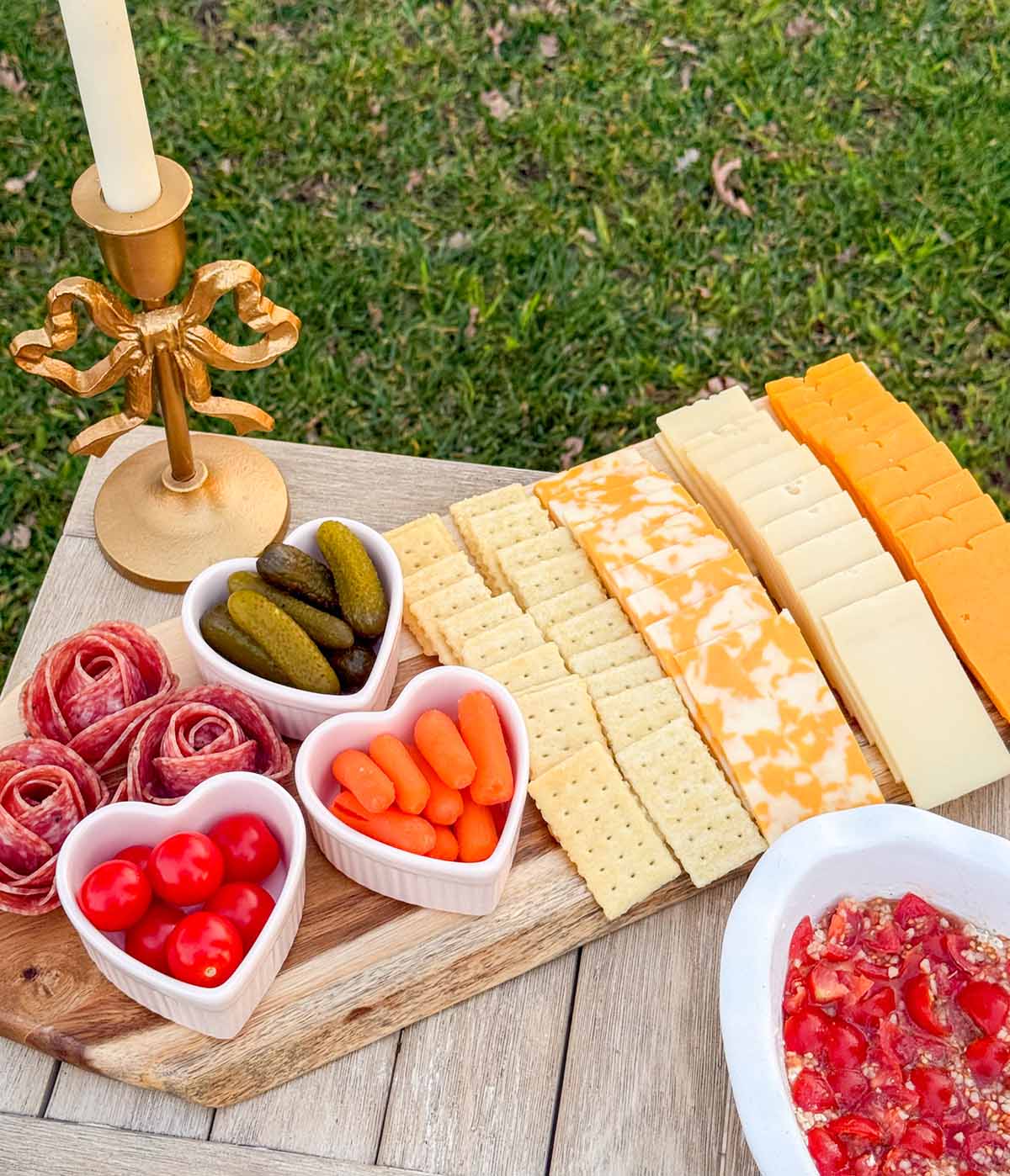 Entertaining expert, journalist and lifestyle blogger Candie Anderson of candieanderson.com shows you how to create a Valentine's Day charcuterie board on a paddle board! She added slices of cheese, crackers, heart shaped ramekins filled with gherkin pickles, baby carrots, and cherry tomatoes. She also adorned it with three salami roses.
