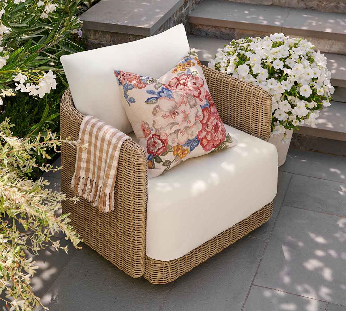 Some outdoor chairs feel overly formal, while others lean so casual they only work in certain spaces. The Pottery Barn Huntington Wicker Swivel Outdoor Lounge Chair lands comfortably in the middle, which is exactly why it feels like such a strong all-around patio piece. The curved shape softens the woven wicker silhouette, giving the chair a more relaxed and welcoming feel that works beautifully in everything from traditional backyard patios to more updated outdoor seating areas. What I like most about this chair is how approachable it feels. The rounded seat cushion and curved back make it look genuinely comfortable instead of stiff or overly styled, and the proportions feel especially practical for everyday use. At just over 32 inches wide, it’s roomy enough for lounging outside with coffee or entertaining friends for a few hours, but it still fits comfortably on smaller patios and porches where oversized outdoor furniture can sometimes feel overwhelming. The lower curved profile also gives it a slightly more casual look than some of the boxier swivel chairs in this roundup. The woven wicker texture helps add warmth and dimension to outdoor spaces without feeling too heavy visually. I could easily see this chair paired with a simple concrete coffee table, layered with striped or gingham outdoor pillows, or styled beside a teak dining table for a more collected patio setup. The swivel base also makes the seating area feel more interactive and relaxed since guests can naturally turn toward different conversations instead of feeling locked into one arrangement. It’s the kind of chair that quietly works with almost everything. Pottery Barn Huntington Wicker Swivel Curved Outdoor Lounge Chair Natural best outdoor wicker swivel chairs