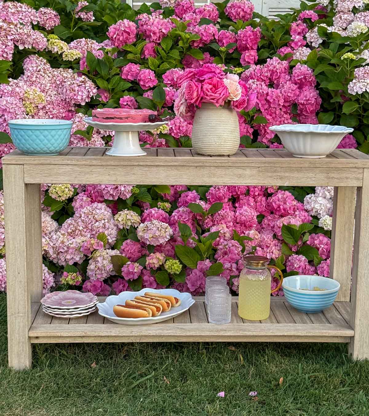 Entertaining expert, journalist and lifestyle blogger Candie Anderson of candieanderson.com shares the outdoor summer entertaining station she created with her outdoor console table in front of her pink hydrangeas.