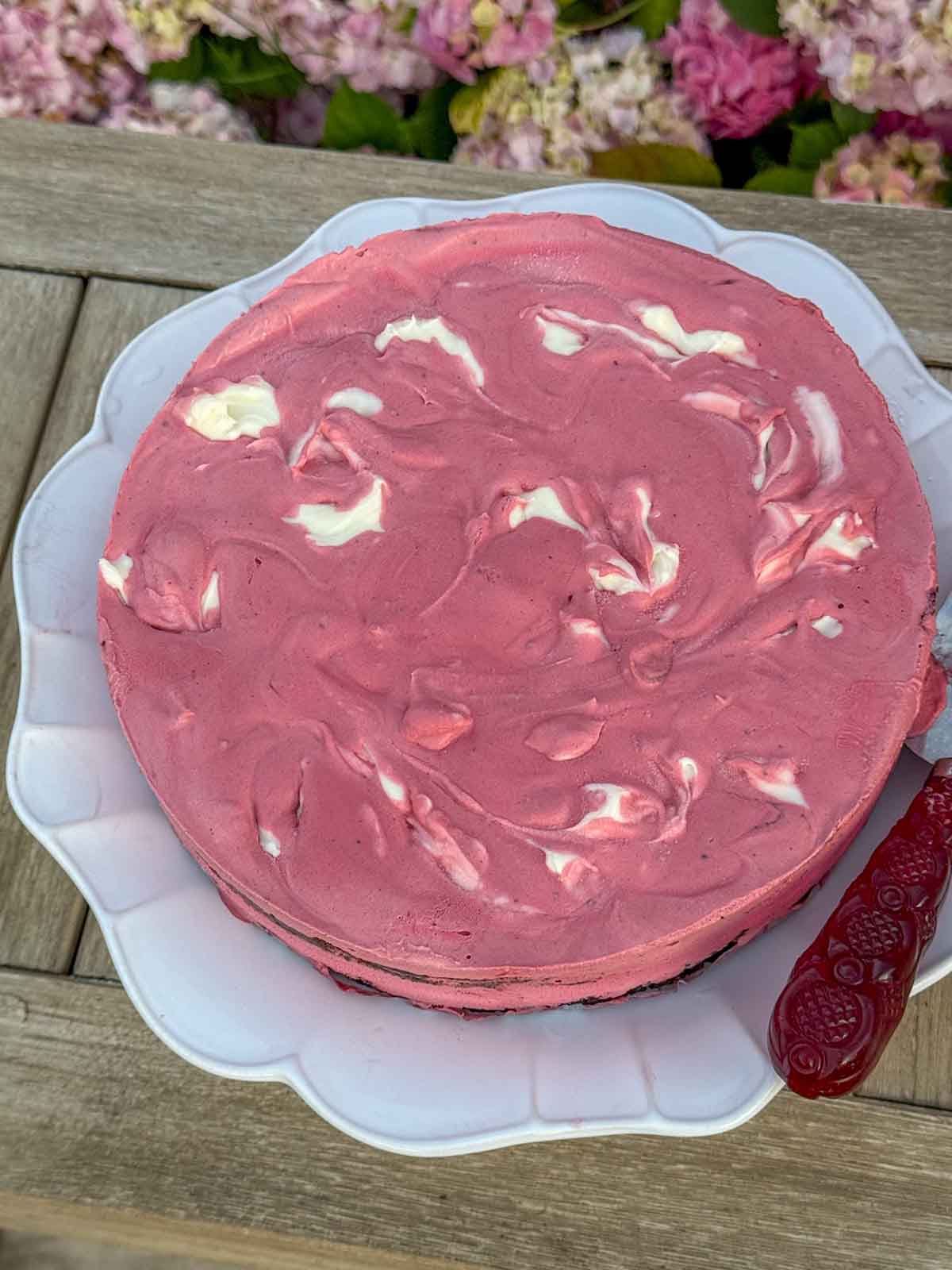 Entertaining expert, journalist and lifestyle blogger Candie Anderson of candieanderson.com shares the red velvet ice cream cake she made on a white cake stand while entertaining friends and family outdoors.