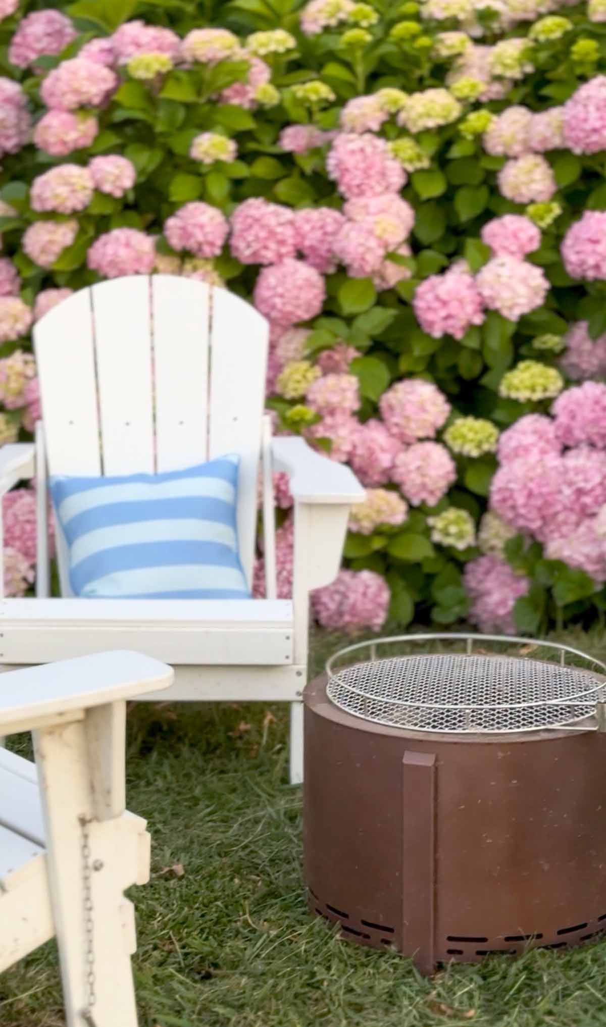Lifestyle expert, journalist and entertaining blogger Candie Anderson of candieanderson.com shares the best smokeless fire pit and white Adirondack chairs in front of her pink hydrangeas.