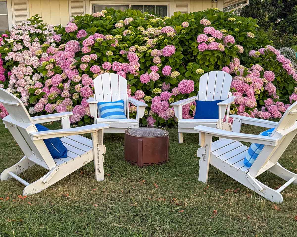 Lifestyle expert, journalist and interior design blogger Candie Anderson of candieanderson.com shares the best white outdoor Adirondack chairs with blue stripe pillows and navy throw pillows and a smokeless fire pit.