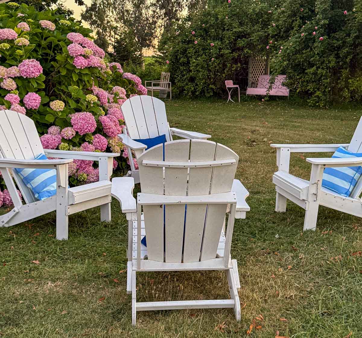 Entertaining expert, journalist and lifestyle blogger Candie Anderson of candieanderson.com shares her gorgeous white Adirondack chairs adorned with blue throw pillows in her hydrangea garden. She shares the most frequently asked questions about outdoor entertaining in the summer.