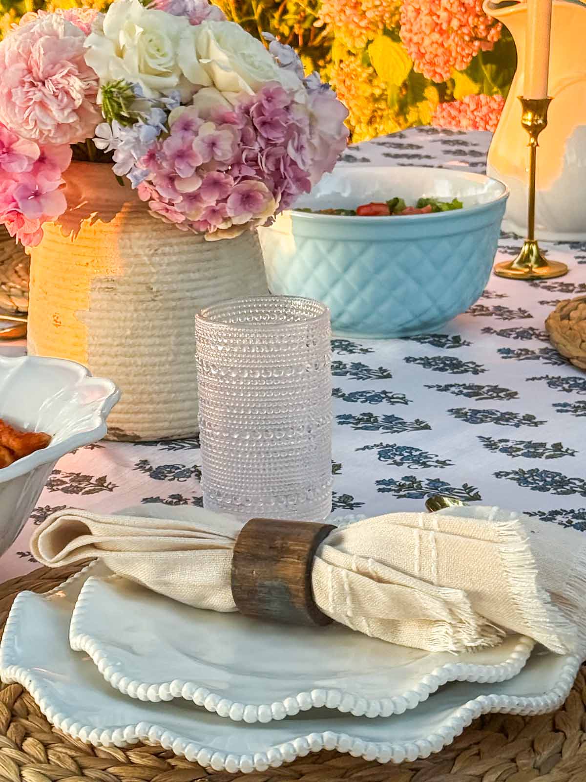 Entertaining expert, journalist and lifestyle blogger Candie Anderson of candieanderson.com shares how she created her beautiful backyard dinner party with beautiful flowers, classic dinnerware, gorgeous brass candleholders, hobnail glasses, a lovely tablecloth, a classic dining table and more!
