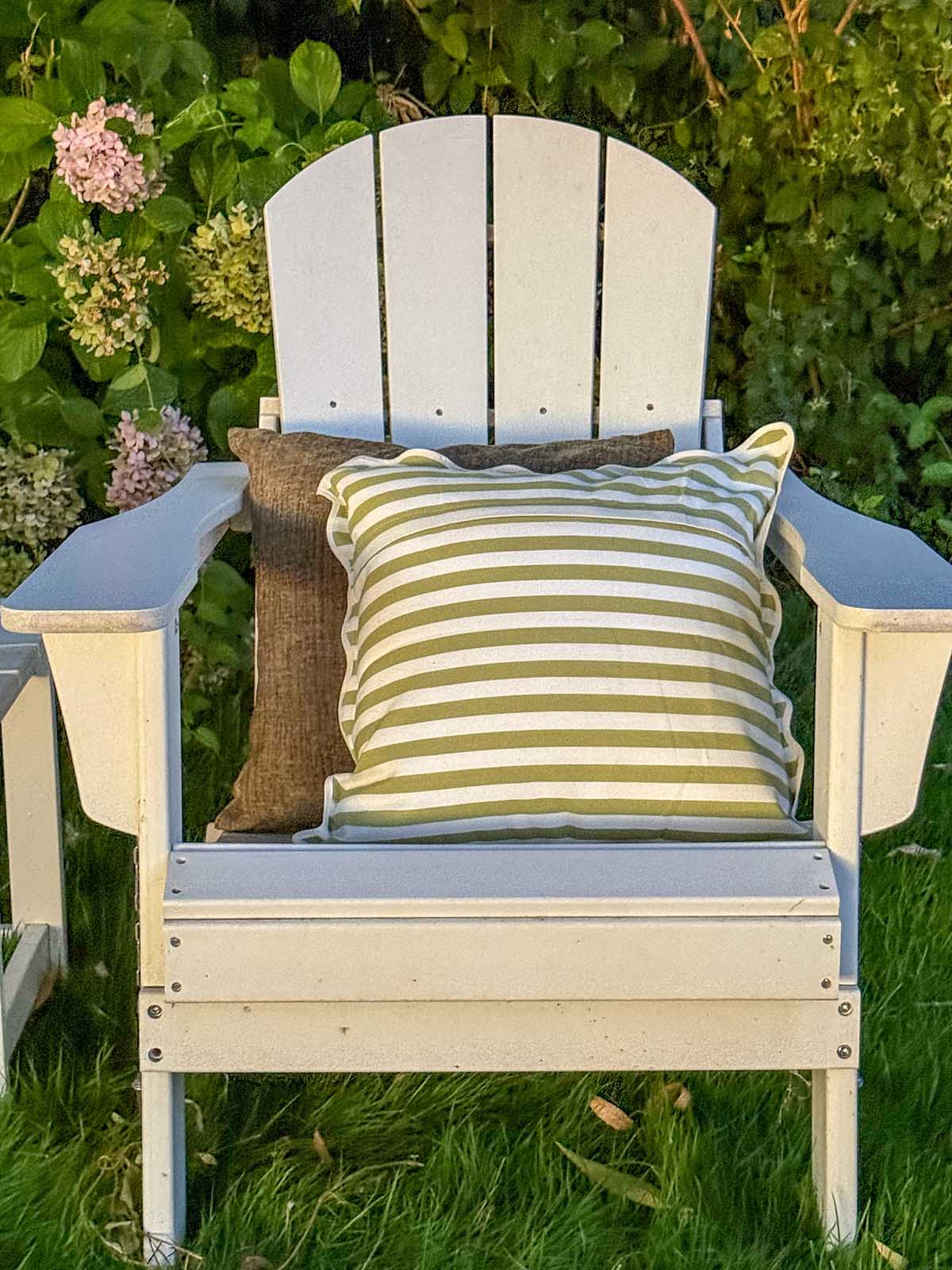 Lifestyle expert, journalist and interior design blogger Candie Anderson of candieanderson.com shares her sage green and scalloped green and white stripe throw pillows on her white Adirondack chair. 