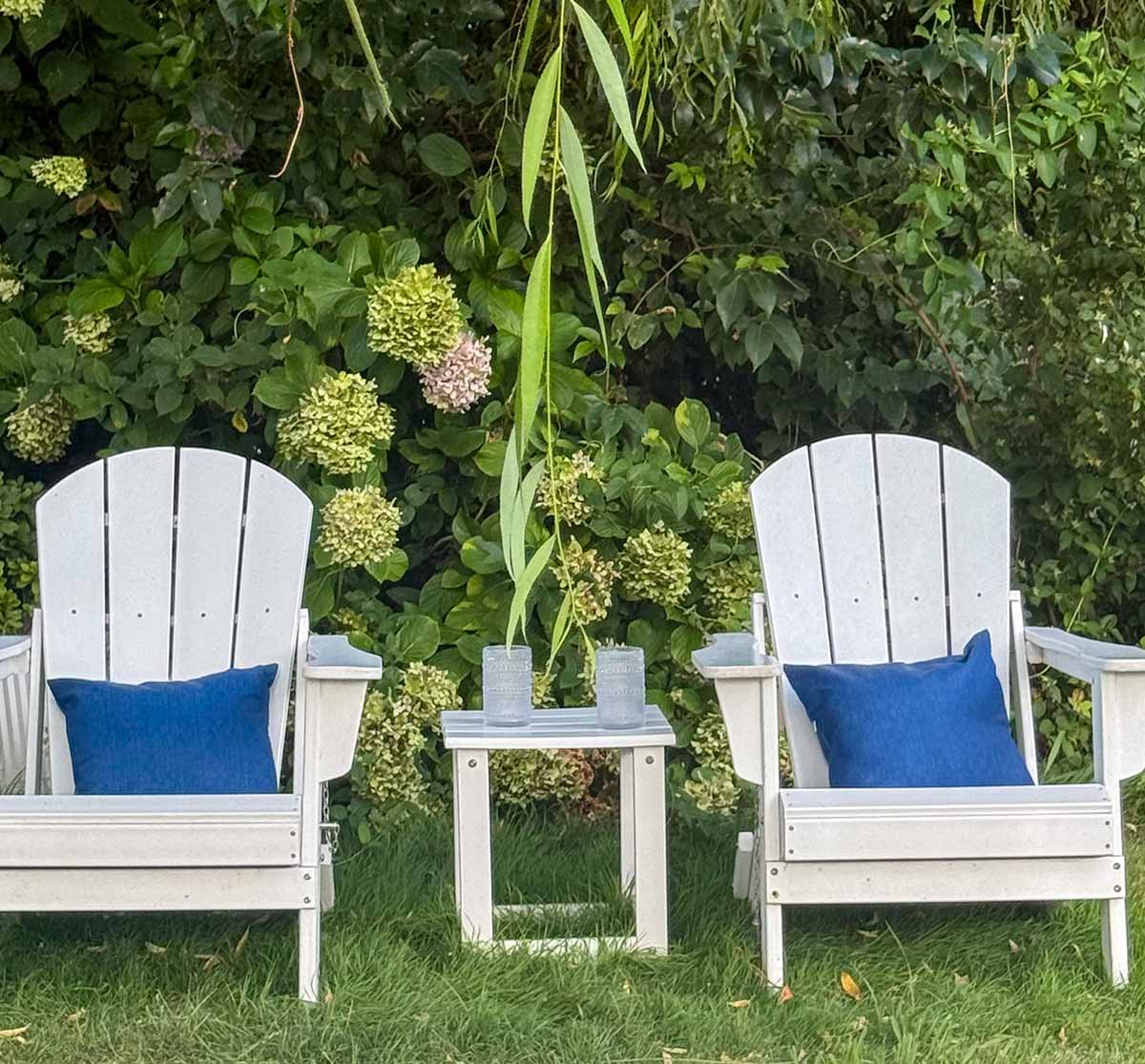 Entertaining expert, journalist and lifestyle blogger Candie Anderson of candieanderson.com shares the best white Adirondack chairs adorned with blue throw pillows.