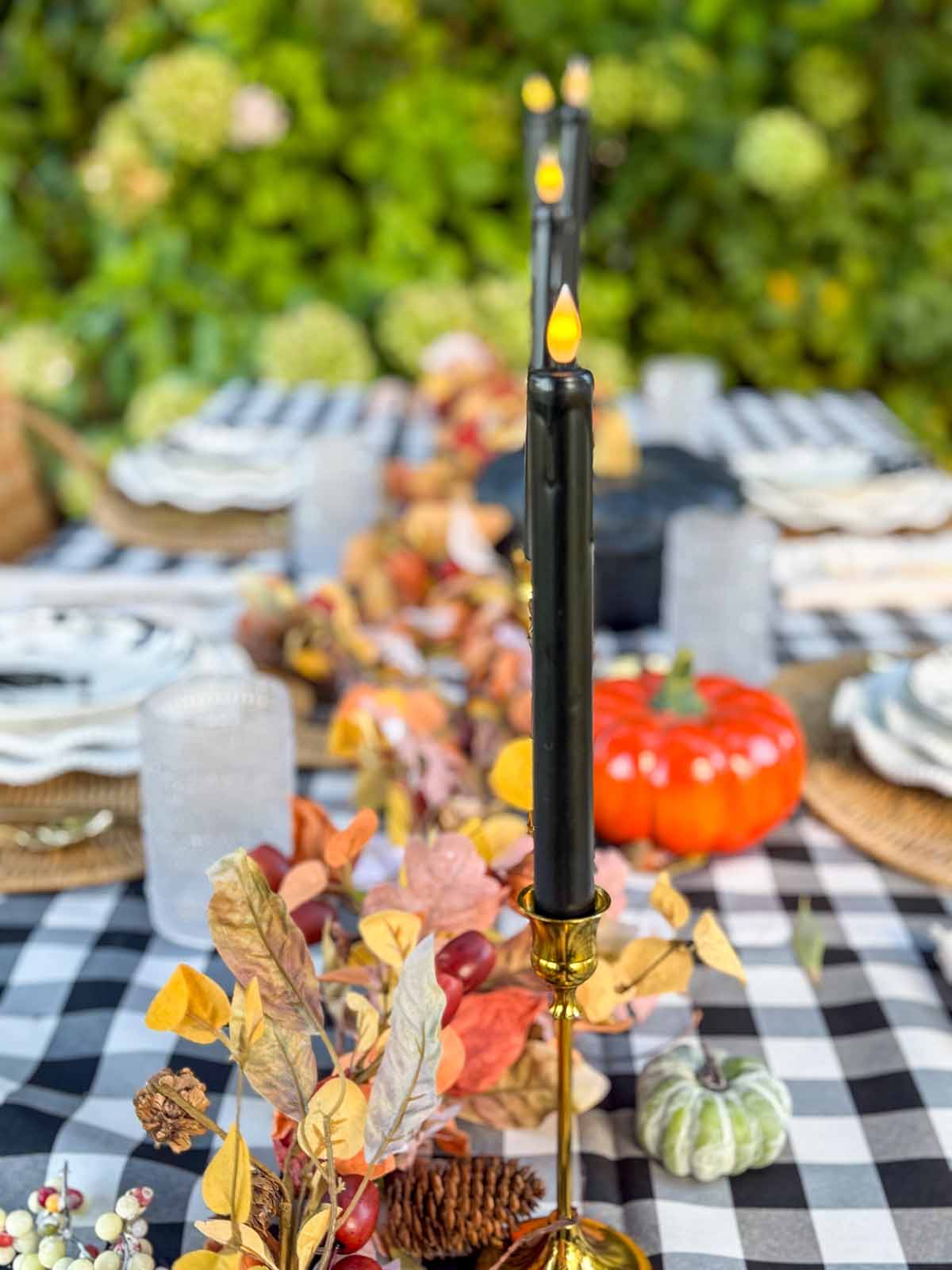 The black taper candles and brass candlestick holders on entertaining expert, Candie Anderson's Halloween tablescape are perfection!