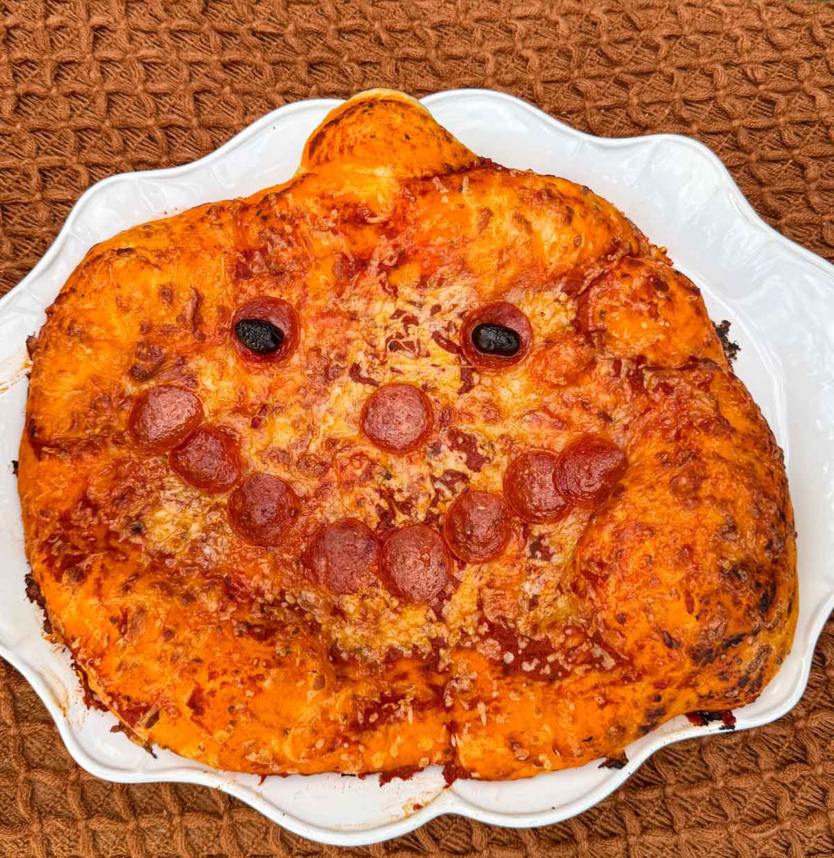 Entertaining expert, journalist and lifestyle blogger Candie Anderson of candieanderson.com shares the adorable pumpkin shaped jackolantern pizza she made on a white ceramic platter.