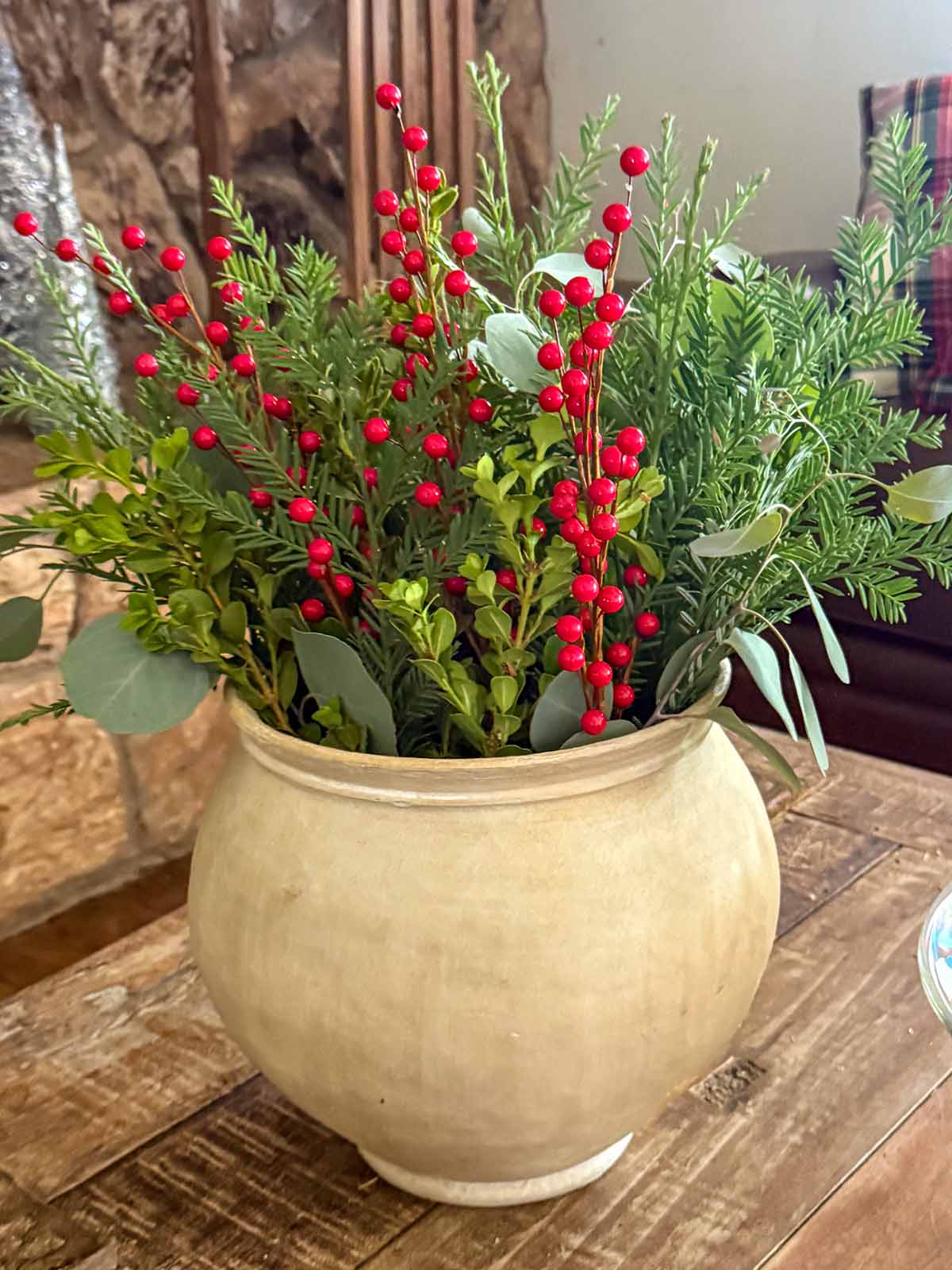 Lifestyle expert, journalist, and interior design blogger Candie Anderson of candieanderson.com shares the beautiful Christmas floral centerpiece she made using real greenery and red berry stems. They look great in her ceramic vase.