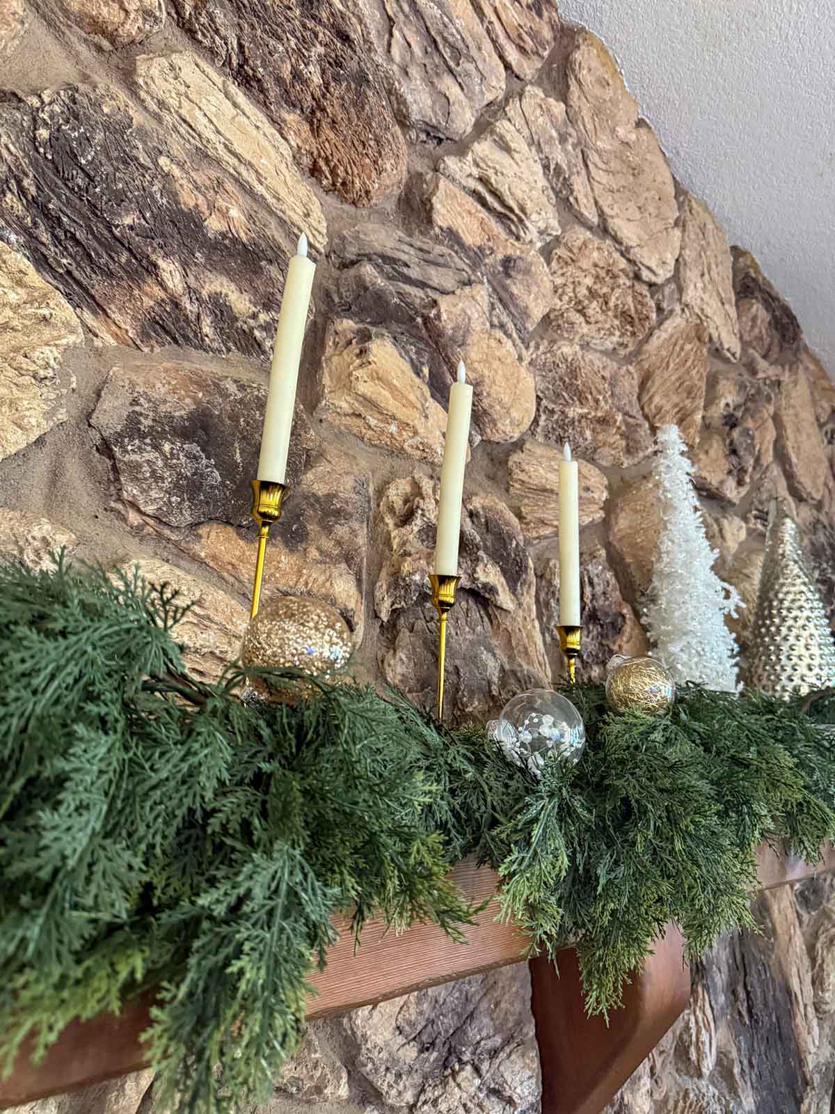 Entertaining expert, journalist and lifestyle blogger Candie Anderson of candieanderson.com shares how she layered her real touch faux cedar garland on her stone fireplace mantel for Christmas.