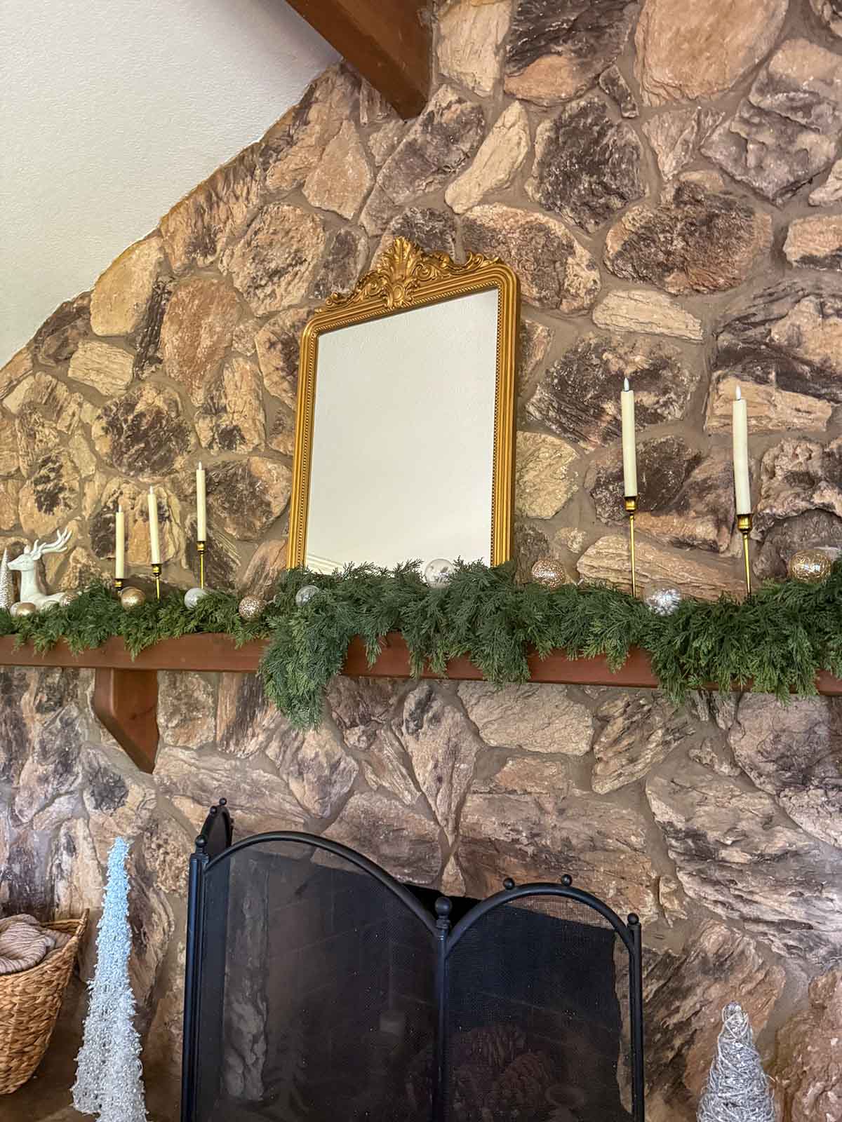Entertaining expert, journalist and interior design blogger Candie Anderson of candieanderson.com shares the gold shatterproof ornaments, gold ornate mirror and faux cedar garland on her stone fireplace mantel.