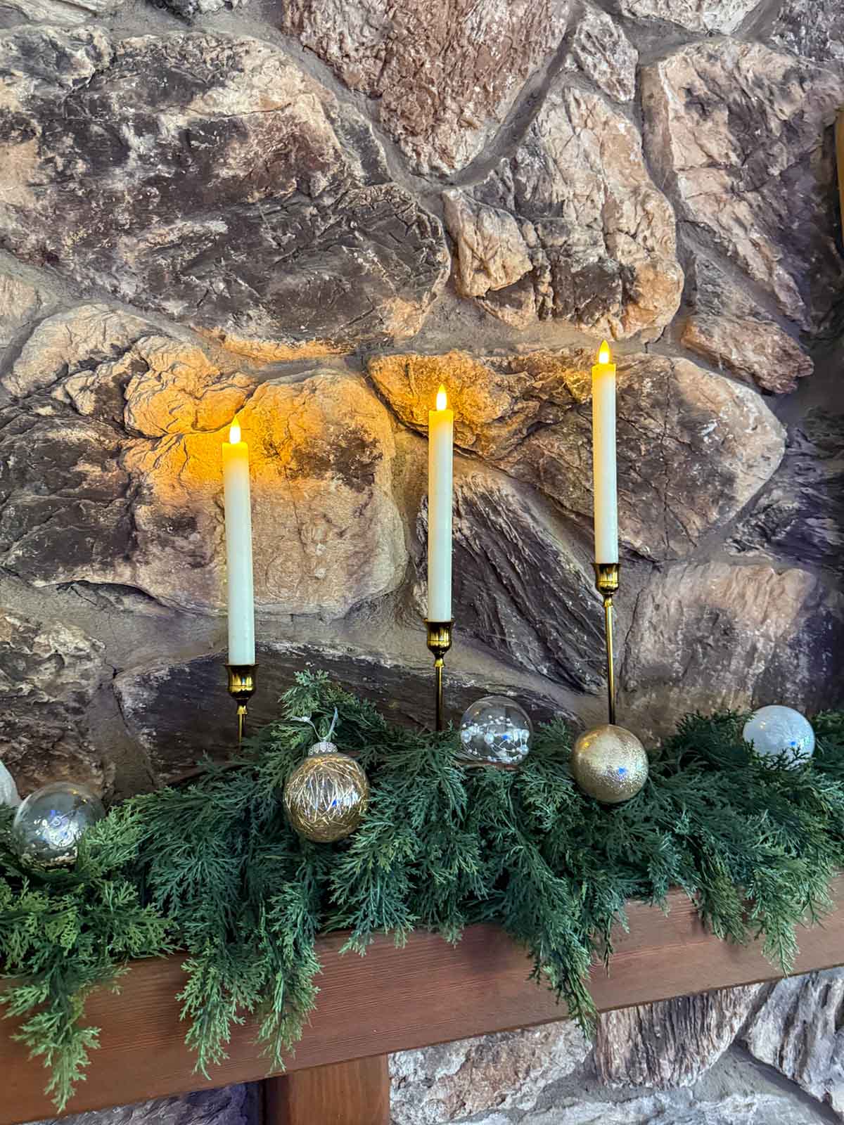 Lifestyle expert, journalist and interior design blogger Candie Anderson of candieanderson.com shares how she decorated her stone fireplace mantel with her gold taper candleholders, battery operated LED flicker candles and faux cedar garland on her mantel.