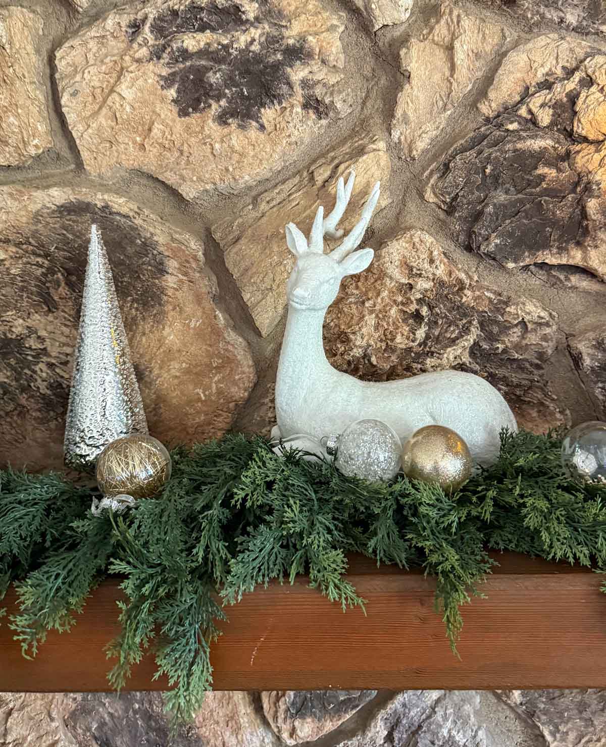 Entertaining expert, journalist and lifestyle blogger Candie Anderson of candieanderson.com shares how she decorated her classic Christmas fireplace mantel with a faux white deer, metallic Christmas trees, and a real touch faux cedar garland.